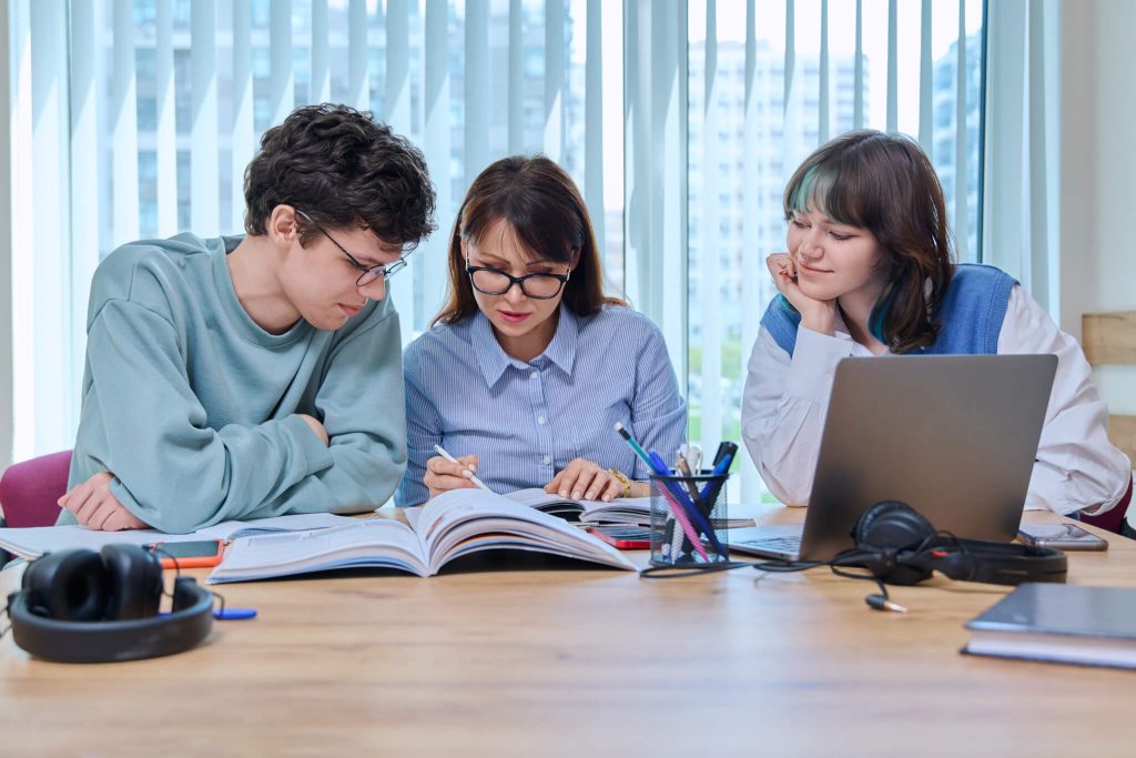 college students with teacher sitting at desk in classroom studying languages sciences.jpg